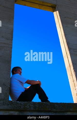 Man sitting on open ledge Stock Photo