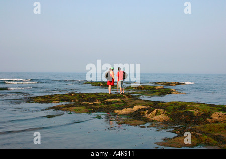 Young couple standing on rocks looking out to sea Stock Photo