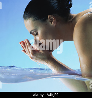 Woman in water cupping hands to face Stock Photo