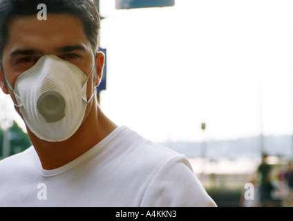 Man wearing white dust mask over nose and mouth, blurred background Stock Photo