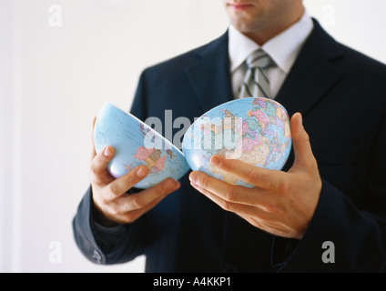 Businessman holding globe halves Stock Photo