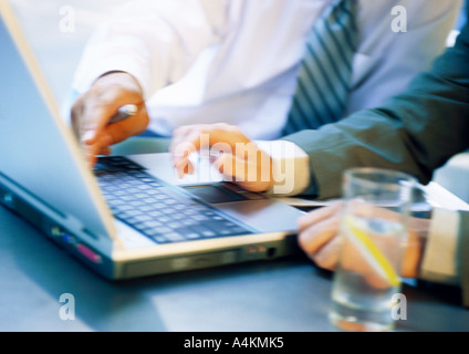 Hands of two businessmen using laptop, close-up, blurred Stock Photo