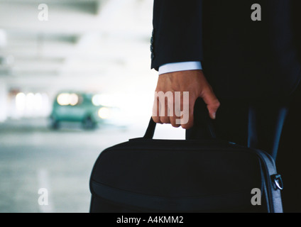 Businessman holding briefcase in parking garage, blurred, close-up Stock Photo