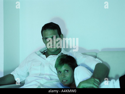 Couple cuddling on sofa, watching scary movie, close-up Stock Photo