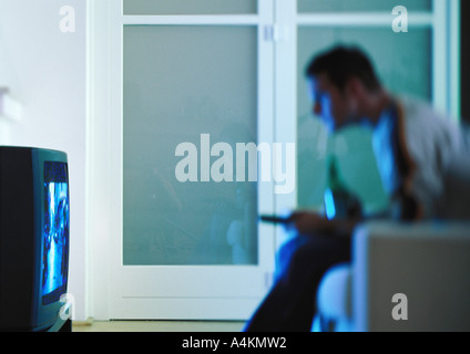 Man with beer watching television, side view, blurred Stock Photo