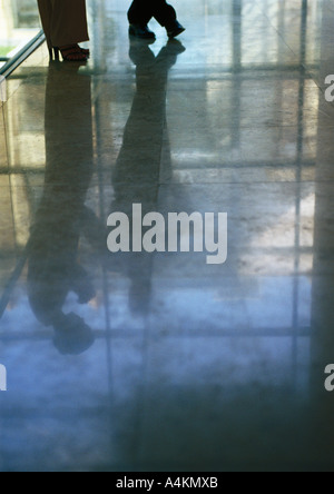 Feet of couple in conversation, reflection on shiny floor Stock Photo