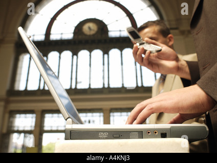 Two businessmen using laptop and cell phone, side view Stock Photo