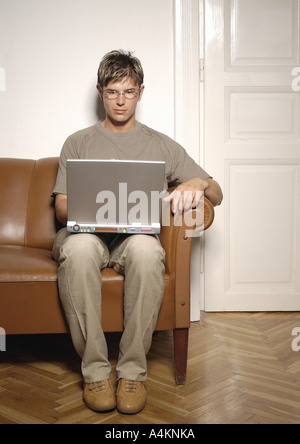 Man sitting on sofa, using laptop computer Stock Photo