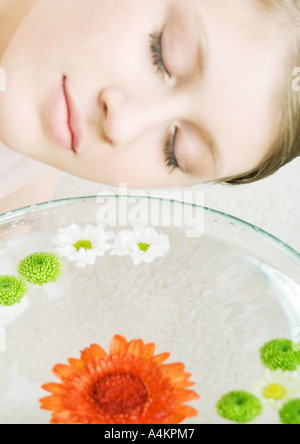 Woman's face and bowl of flowers floating in water Stock Photo