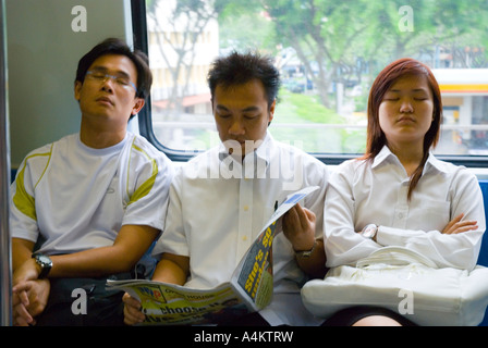 Tired workers on their way home from work dozing on a train in Singapore Stock Photo