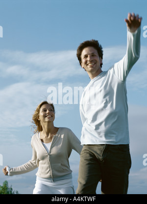 Young man and young woman walking hand in hand with arms out Stock Photo