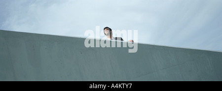 Man standing behind concrete wall, low angle view Stock Photo