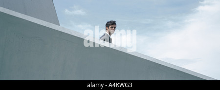 Man standing behind concrete wall, low angle view Stock Photo
