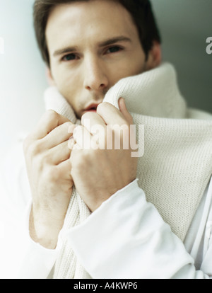 Man holding sweater around neck, covering part of face Stock Photo