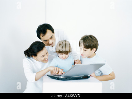 Boy and little girl with parents using laptop together Stock Photo