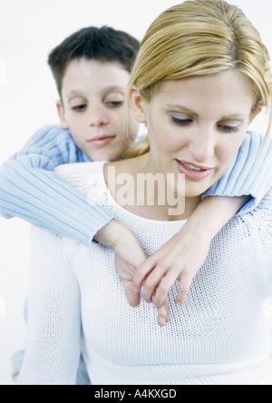 Boy behind woman with arms around shoulders Stock Photo