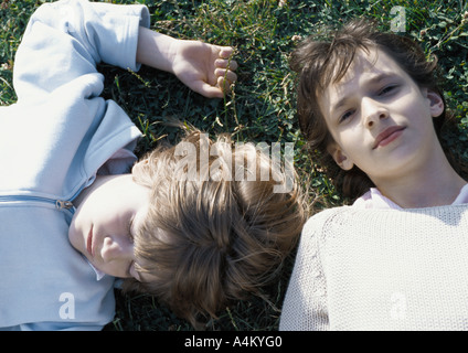 Girl and boy lying on grass Stock Photo