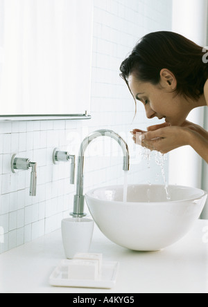 Woman bending over sink, washing face Stock Photo