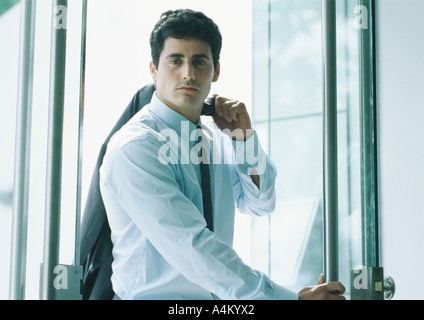 Businessman holding suit jacket over shoulder, coming through door, portrait Stock Photo