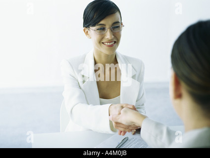Two women in suits shaking hands Stock Photo