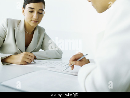 Two women sitting across from each other, one filling in application Stock Photo