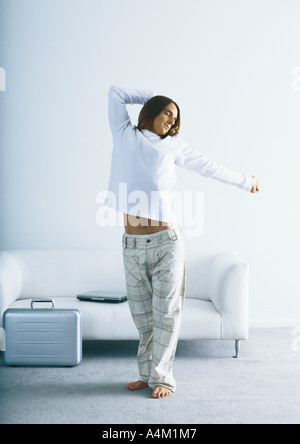 Man stretching in front of sofa and briefcase Stock Photo
