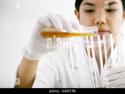 Woman transferring contents of test tube Stock Photo