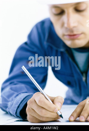 Man concentrating on writing or drawing at a table in warm sunlight ...
