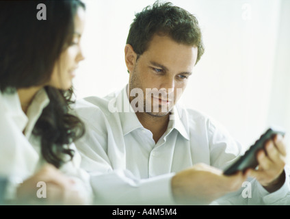 Young couple considering figure displayed on calculator Stock Photo