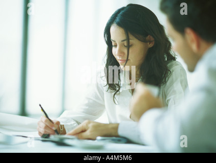 Young adults examining documents, woman holding pencil as man points Stock Photo