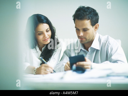 Young adults examining documents, calculating Stock Photo