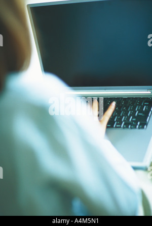 Woman typing on laptop, over the shoulder view Stock Photo