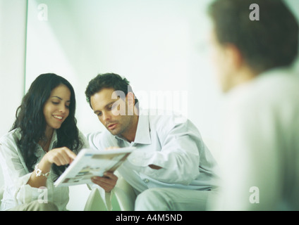 Young adults examining catalog Stock Photo