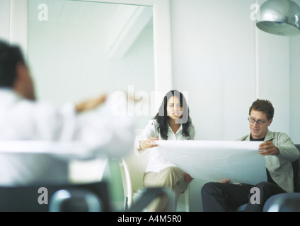 Young adults examining blueprints Stock Photo