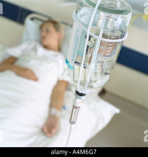 IV and female patient lying in hospital bed Stock Photo