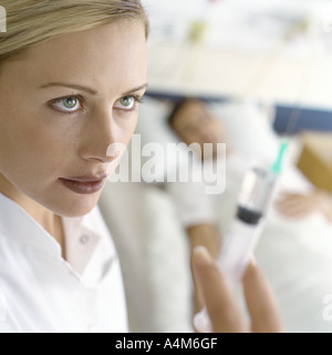 Nurse holding up syringe in front of patient Stock Photo
