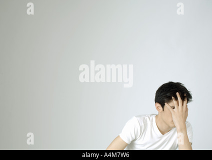 Young man covering face with hand Stock Photo