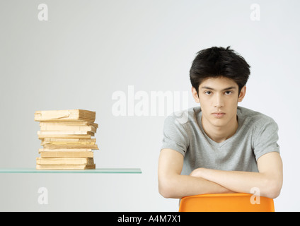 Young man sitting next to stack of books, portrait Stock Photo