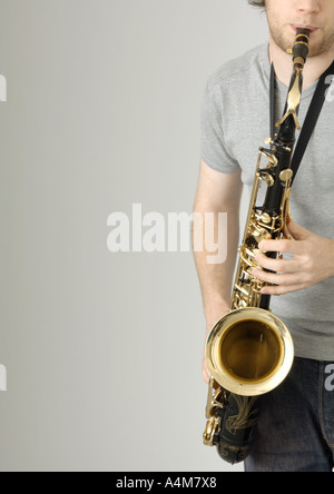 Young man playing saxophone, partial view Stock Photo