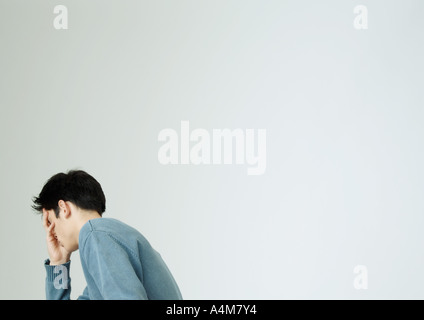 Young man covering face with hand Stock Photo