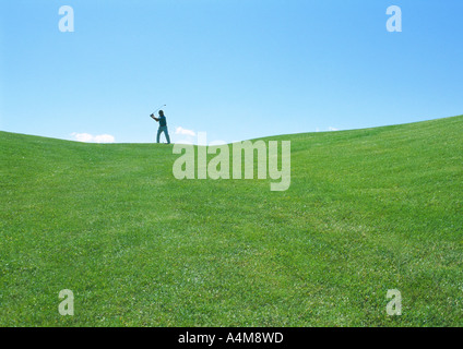 Golfer swinging in distance Stock Photo