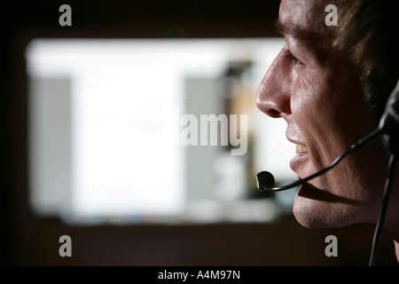 Male person is talking on the phone, Internet, Voice over IP,  using a headset, in front of a computer monitor. Stock Photo