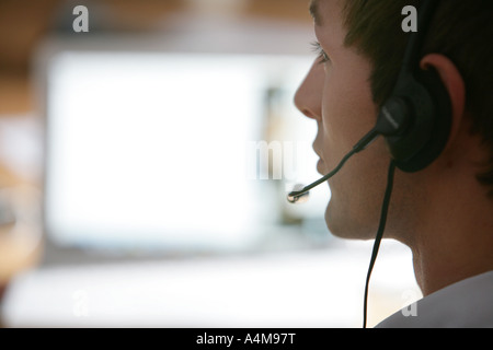 Male person is talking on the phone, Internet, Voice over IP,  using a headset, in front of a computer monitor. Stock Photo