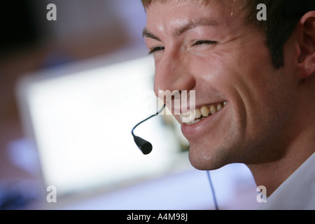 Male person is talking on the phone, Internet, Voice over IP,  using a headset, in front of a computer monitor. Stock Photo