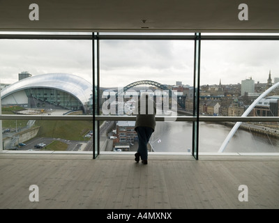 A man looking at the Newcastle bridges and Sage concert hall from the viewing box at the Baltic Mills Art Gallery in Gateshead Stock Photo