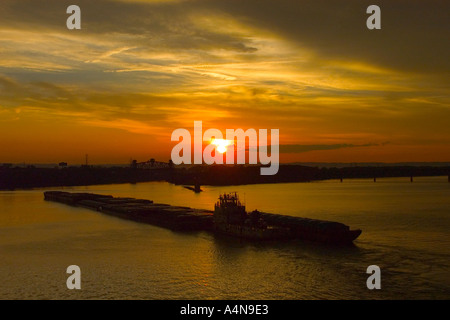 Tugboat pushing coal barges toward the McAlpine locks on the Ohio River at Louisville Kentucky at sunset Stock Photo