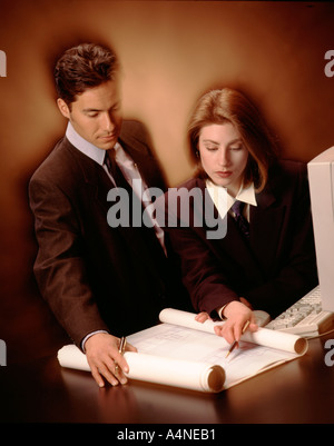 Businessman and businesswoman working on blueprints in office. Stock Photo