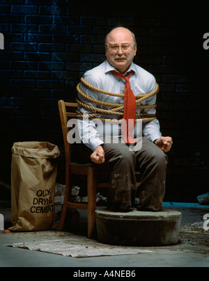 Businessman tied up with feet in cement Stock Photo