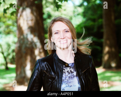 portrait of 30  woman smiling in wood hair blowing in the wind Stock Photo