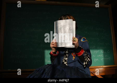 A middle school girl wearing boy scout uniform sitting in front of  a blackboard. Stock Photo